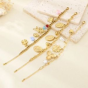Detail of three gold charms bracelets featuring angels, crosses and daisy pendants