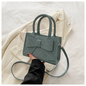Detail of sage green woven texture handbag with oversized bow and dual handles