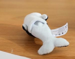 Detailed view of plush orca toy material and product labels on a wooden background