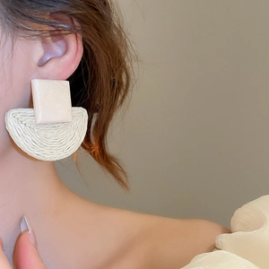 Macro shot of cream raffia woven semi-circle drop earrings with geometric wooden square stud