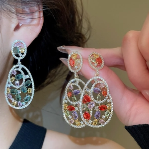 Macro shot of silver drop earrings with colorful zircons in a vintage hollow oval design