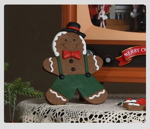 Detail of gingerbread man figurine with green overalls on a white lace tablecloth