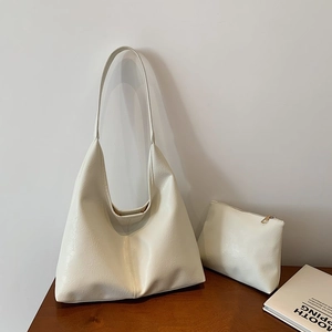 Set borsa hobo bianco crema minimalista con piccola pochette a zip su scrivania in legno