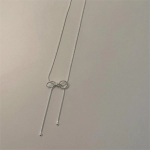 Close-up of a minimalist 925 sterling silver bow snake chain necklace with bead details