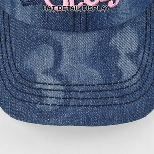 Dettaglio del cappellino da baseball in denim blu con cuciture multiple e ricamo rosa
