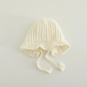 Detailed cable knit pattern and scalloped lace edge on this off-white baby bonnet