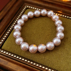 Detailed view of pink pearl bracelet on a vintage green velvet display stand