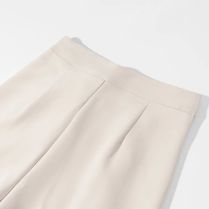Detail shot of beige high-waist trousers featuring precise stitching and smooth fabric