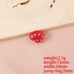 Vista macro di un ciondolo a conchiglia in vetro rosso con punti blu per gioielli DIY