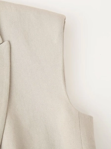 Macro detail of the beige woven fabric texture and shoulder stitching on sleeveless vest