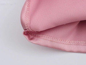 Gros plan montrant les coutures et l'ourlet du tissu brillant rose sur le pantalon