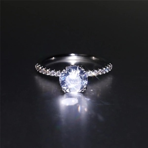 Macro shot of silver ring with six-prong set round diamond and pavé band detailing