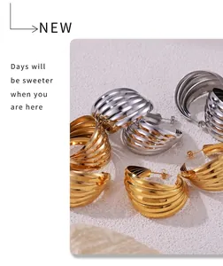 Close-up of gold and silver layered wavy metal earrings on a textured white background