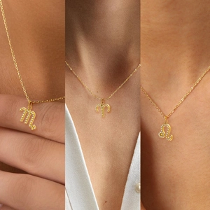Detailed close-up of Scorpio Aries and Leo zodiac pendants on gold titanium necklaces