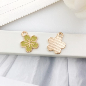 Detail of cherry blossom alloy pendant showing green enamel front and gold back side