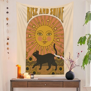 Detailed view of bohemian tapestry with sun and black cat hung in a warm room