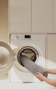 Detailed view of rolled gray plush bath mat showing thick texture in a laundry room