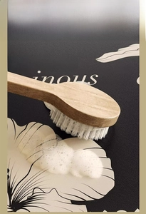 Close-up of wooden brush cleaning a quick-dry absorbent bathroom mat with white foam