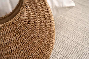 Detailed close-up showing the brown woven texture and natural fibers of the straw bag