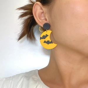 Close-up of Halloween earring featuring a yellow crescent moon and black bat on a model