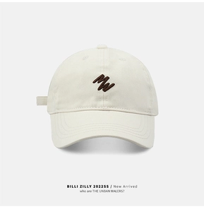 Detail of light beige baseball cap showing brown MW letter embroidery and 6-panel design