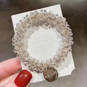 Close-up of pale pink beaded elastic hair tie with a small round metal brand charm