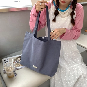 Detailed close-up of greyish blue canvas tote bag showing metal magnetic closure and wide strap