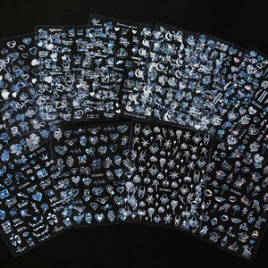 Detailed flat lay of holographic heart and love themed nail stickers on black background
