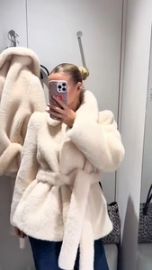 Detail of cream faux fur coat with oversized lapels and matching waist belt