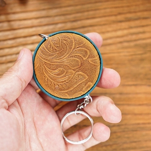 Close-up of handmade crazy horse leather mini tape measure with floral embossed patterns