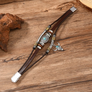 Detail of multi-strand brown leather bracelet with turquoise bull head pendant on wood