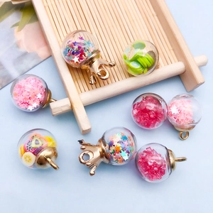 Detail of colorful star sequins and fruit clay slices inside mini glass bottle pendants
