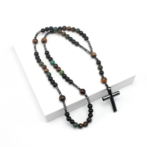 Detail of beaded cross necklace with tiger eye and turquoise stones on white stand