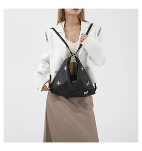 Detail of the black nylon shoulder bag featuring a stylish bow decoration on the side