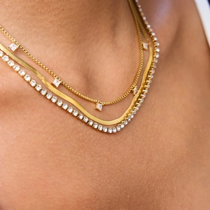 Gros plan d'un collier triple rang en plaqué or 18 carats avec maille serpent et tennis