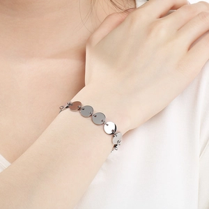 Close-up of minimalist silver stainless steel bracelet featuring polished circular discs