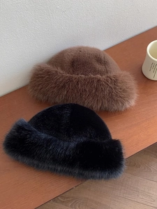 Detailed view of plush faux fur bucket hats in brown and black on a wooden table