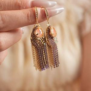 Detail of bohemian gold tassel earrings with peach drop stones and purple beadwork
