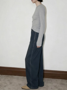 Detail of grey slim long sleeve top paired with high waist dark blue wide leg jeans