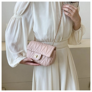 Pink quilted chain crossbody bag with pleated texture and golden twist lock on model