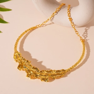 Macro view of gold statement necklace featuring irregular lava texture and abstract leaf design