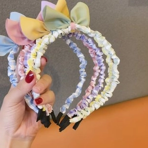 Detail showing various pastel pleated fabric headbands with cute bows in multiple colors