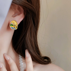 Close-up of vintage enamel pearl earrings in gold green and blue worn by a model