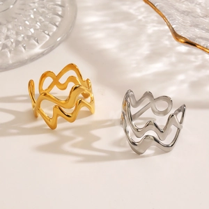 Minimalist 18K gold and silver wavy crisscross rings on a clean aesthetic background