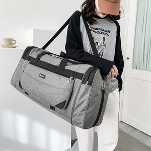 Detailed view of gray nylon travel bag with SPORT logo being worn by a male model