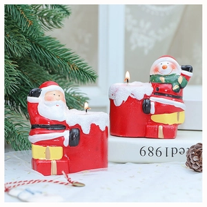 Close-up of Santa Claus and snowman paraffin candles with festive snowy details