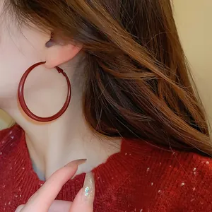 Elegant large circular Ancora red enamel hoop earrings worn by a female model