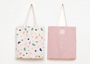 Detail of canvas tote bags featuring geometric patterns and Donut Worry Be Happy embroidery