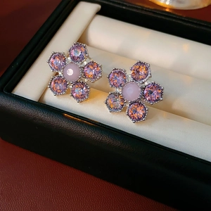 Gros plan de boucles d'oreilles fleurs en argent avec cristaux violets et perles roses en boîte