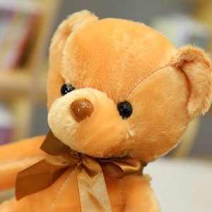 Primer plano detallado de un suave oso de peluche naranja con un bonito lazo de raso marrón